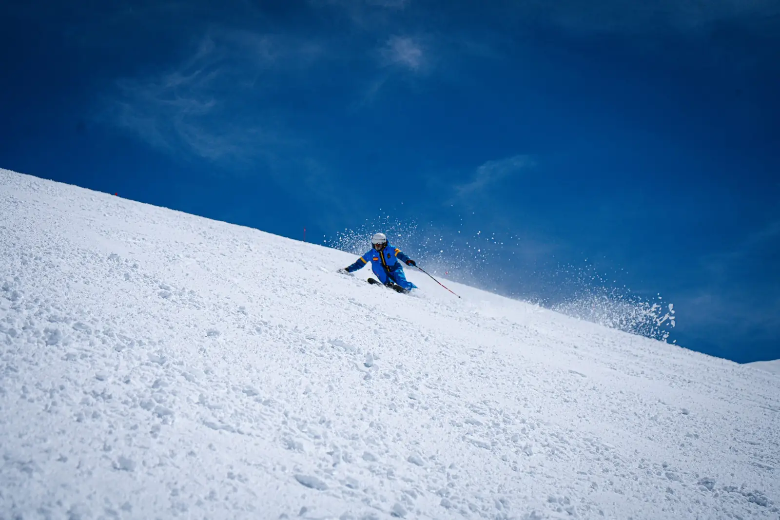 Profesor de la Escuela Española de Esquí bajando una pista de Sierra Nevada bajo el cielo azul
